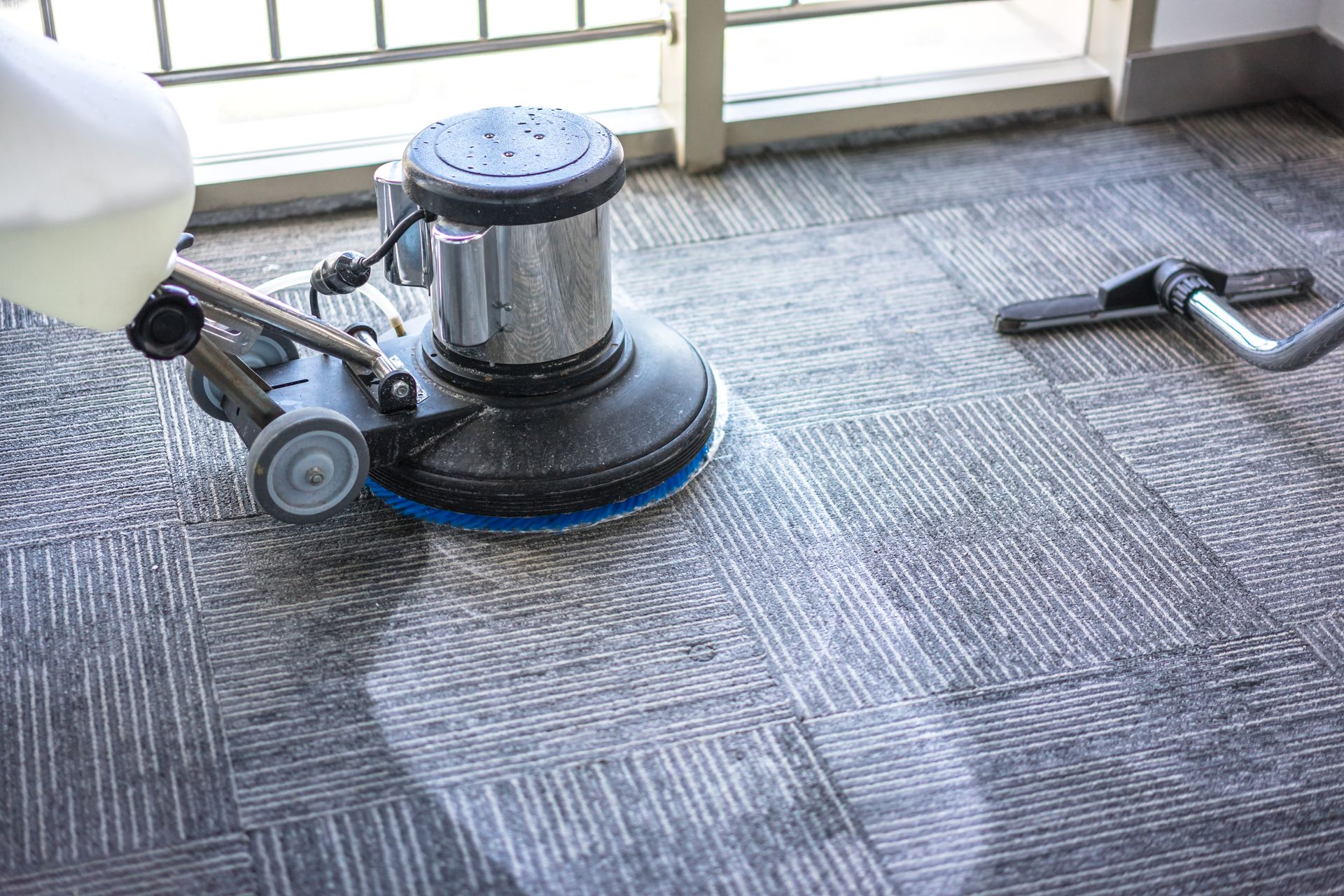 Professional carpet cleaning machine on office floor tiles with cleaning supplies